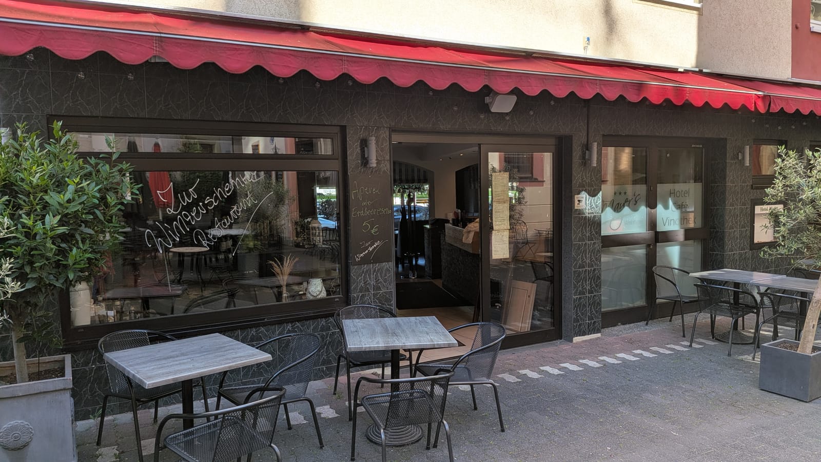 Außenansicht mit Terrasse unter der roten Markise